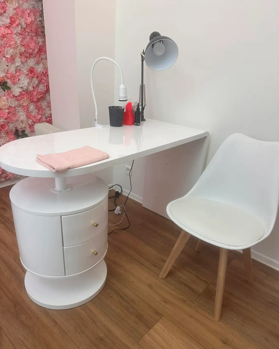 Le poste de travail de l’institut : table blanche, lampe et mur de roses